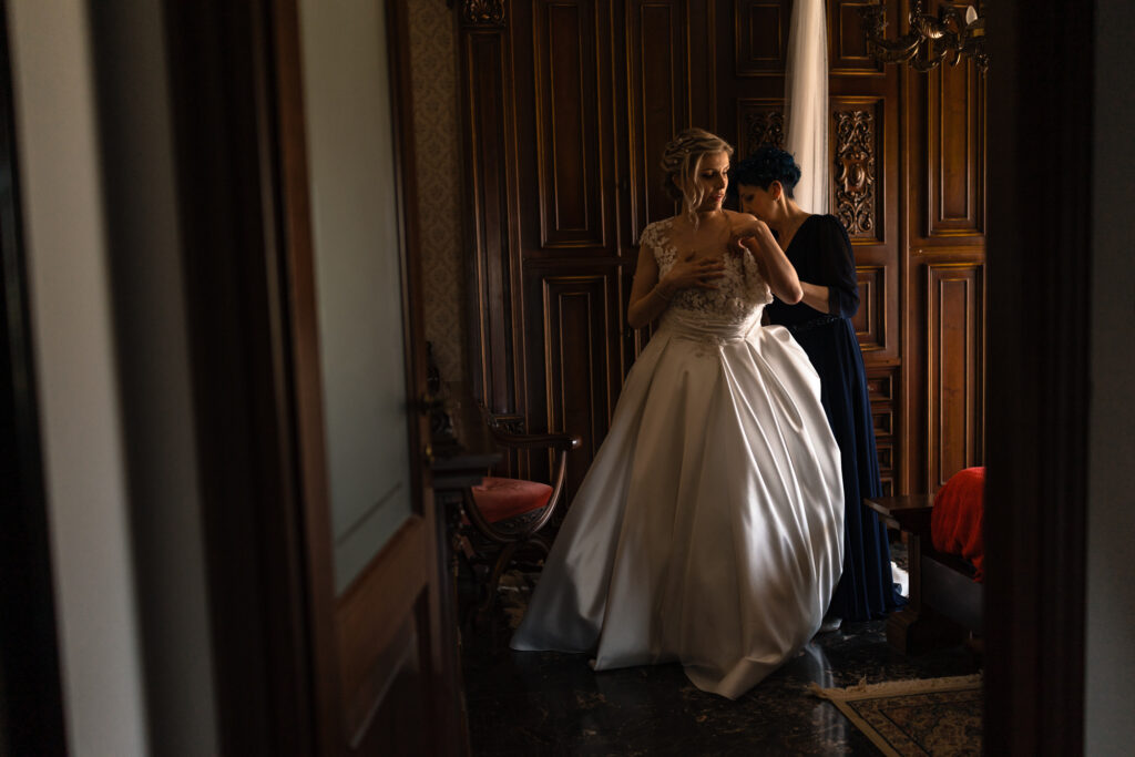 Preparazione della sposa mentre le sistemano l’abito