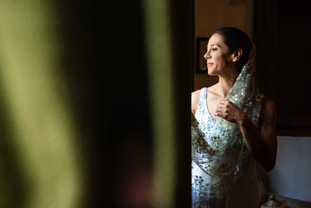 La sposa controlla dalla finestra felice e raggiante per la giornata unica 