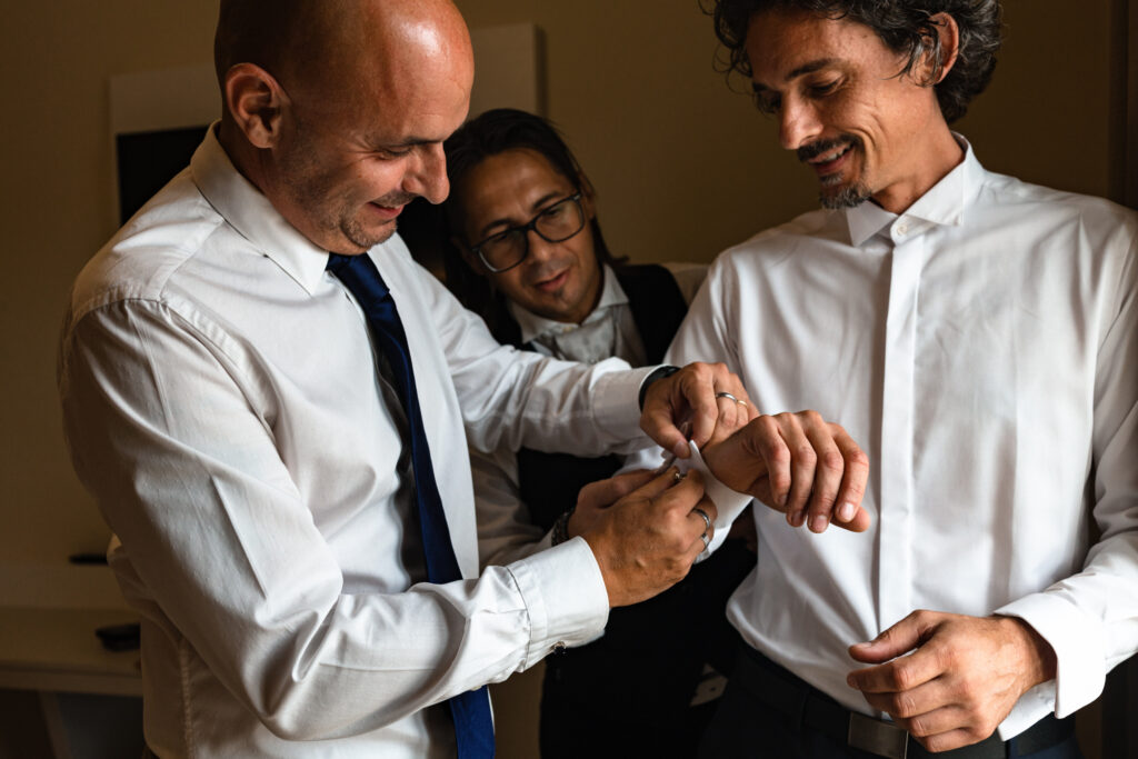 Il testimone aiuta lo sposo a mettere i gemelli 